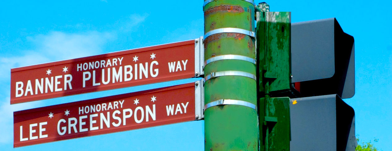 A street sign displaying two distinct street names mounted on a single post against a clear sky backdrop.