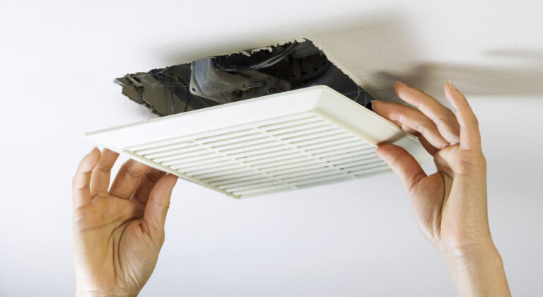 Hands removing bathroom exhaust fan cover