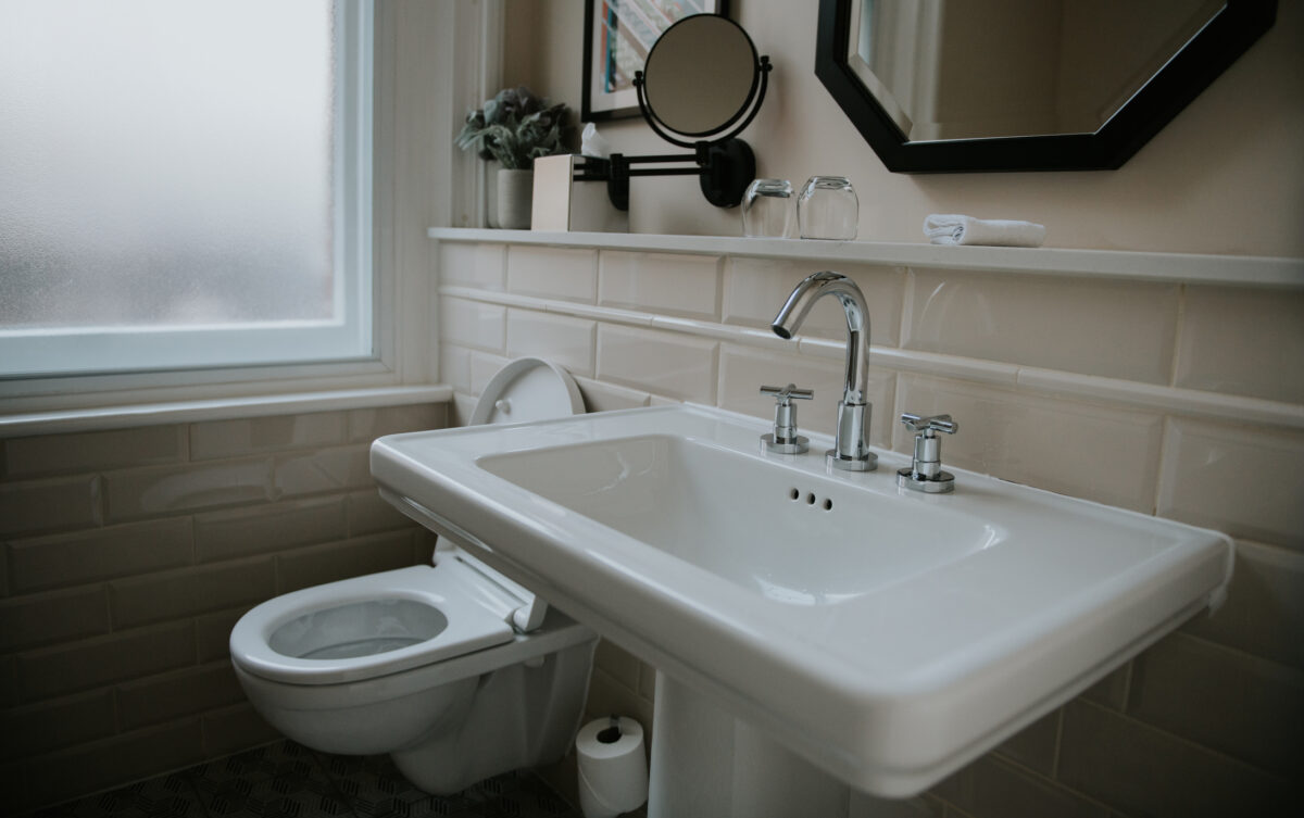 Pedestal bathroom sink next to toilet in home bathroom
