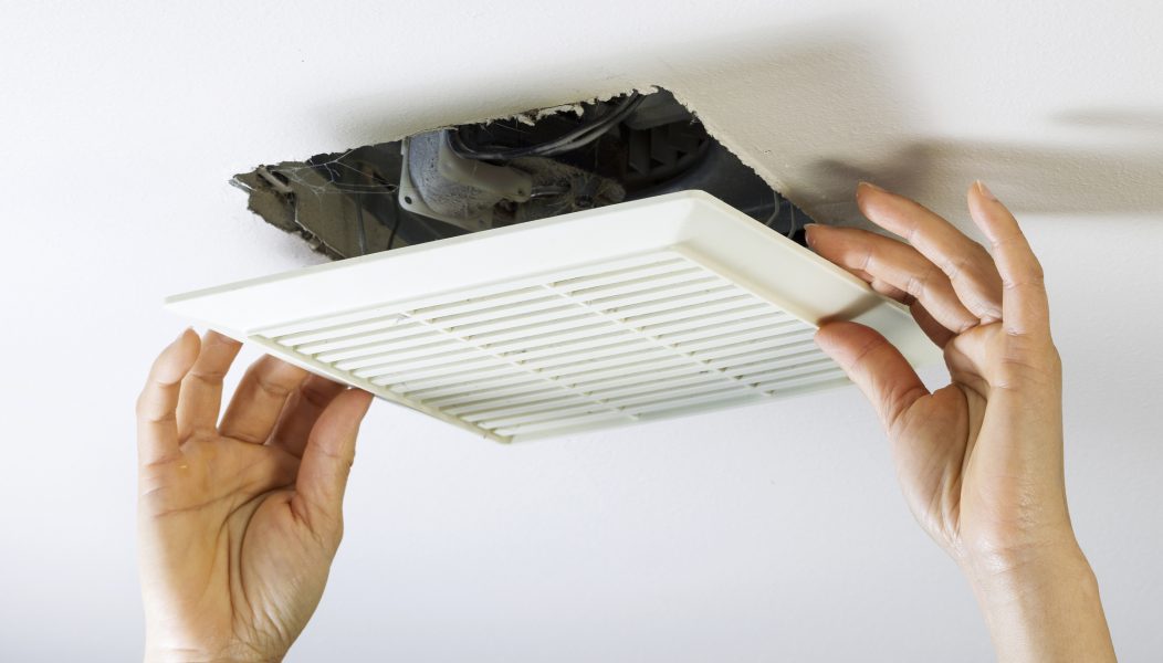 Hands removing bathroom exhaust fan cover